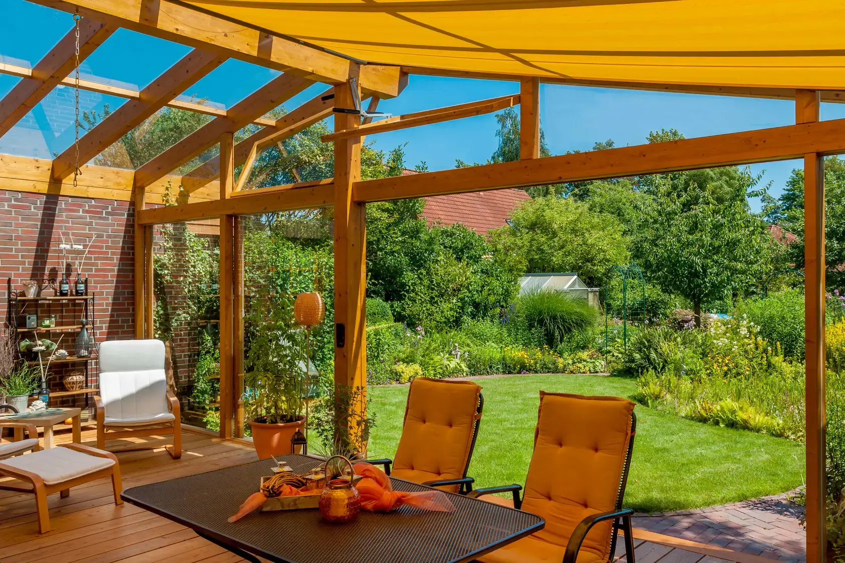 Blick aus gemütlichem Wintergarten in den großen Naturgarten im Sommer