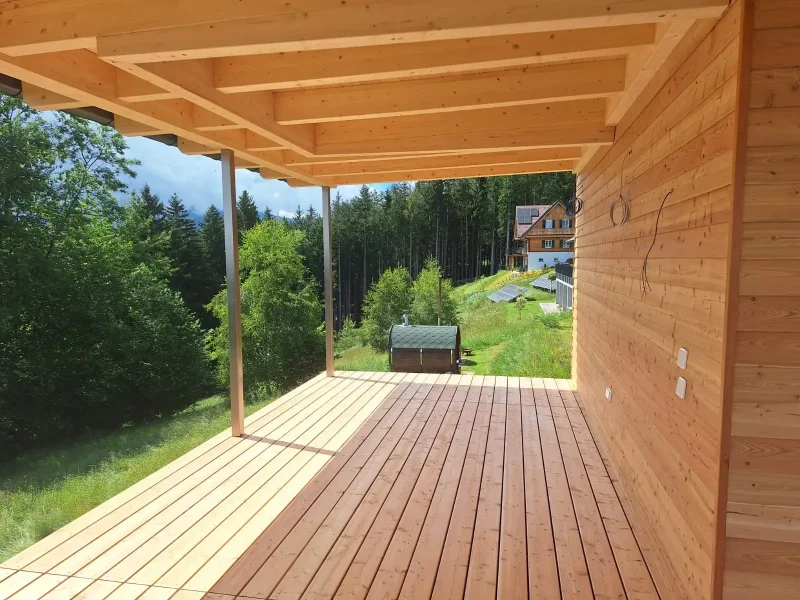 Modernes Holzhaus mit großzügigem Dachüberstand, sichtbarer Holzkonstruktion und schlanken Stahlstützen.